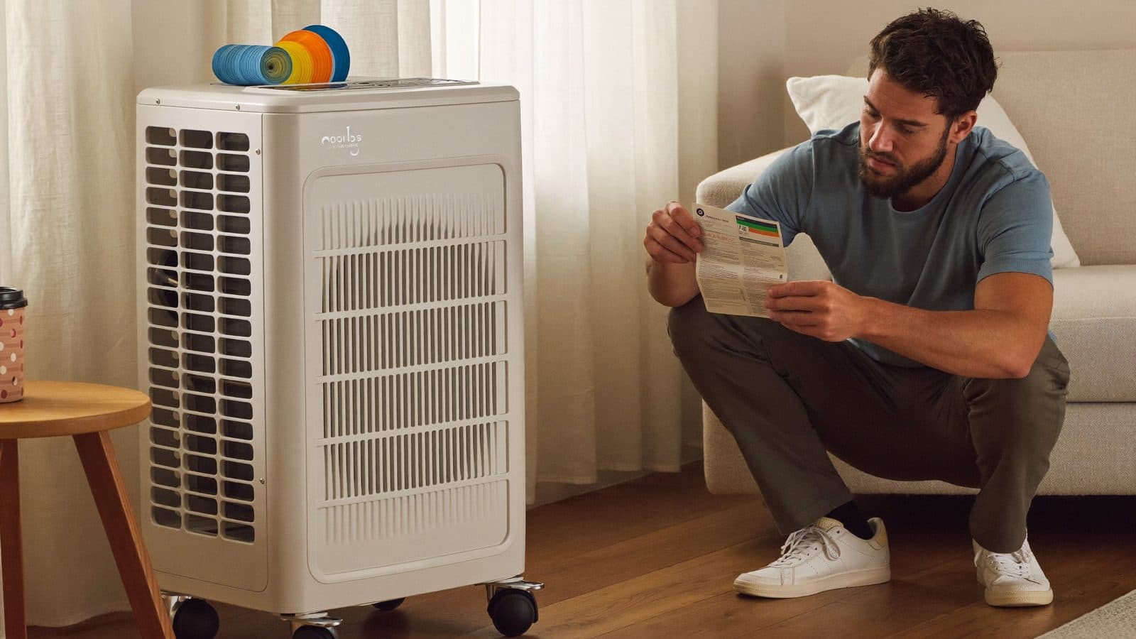 Man bekijkt het energielabel van een verrijdbare airco in een Nederlandse woonkamer